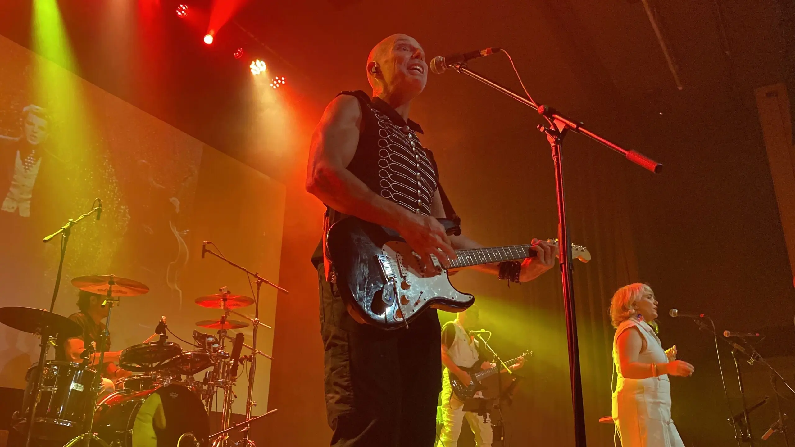 Duncan Barnett playing guitar and singing, with Marlisse Kalt in the background